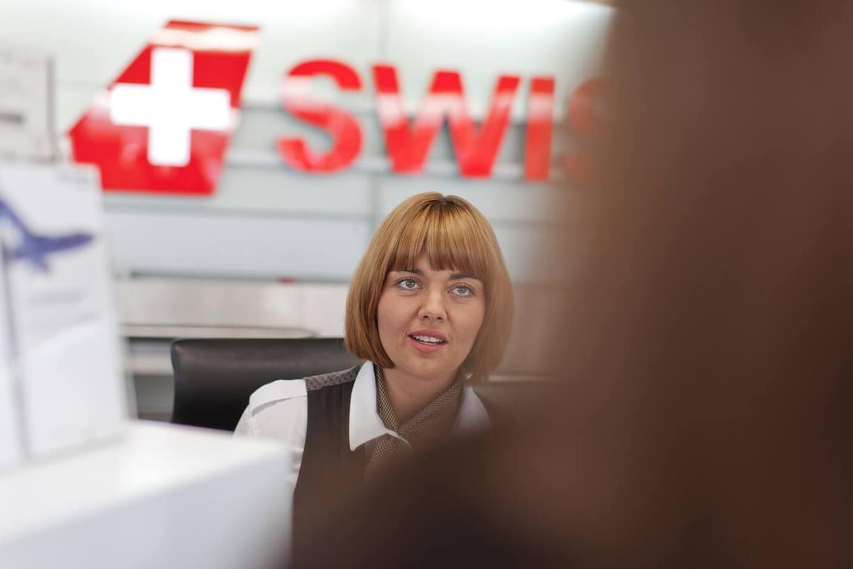 Eine Mitarbeiterin der Fluggesellschaft swiss bedient eine Kundin am Check in in der Halle 1 am Flughafen in Zuerich, aufgenommen am 7. August 2012. (KEYSTONE/Gaetan Bally) [GESTELLTE AUFNAHME]