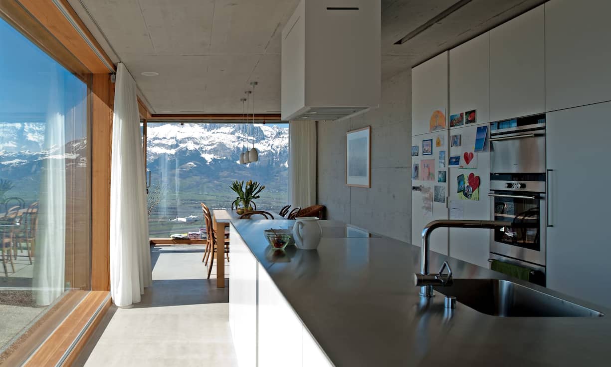 Auf 786 Metern, oft über dem Nebelmeer, liegt der Neubau im Dorf Planken. Vom offenen Küchen-Ess-Bereich wie vom Home Office unter demselben Dach sieht man durch grosse Panoramascheiben auf die Schweizer Berge.