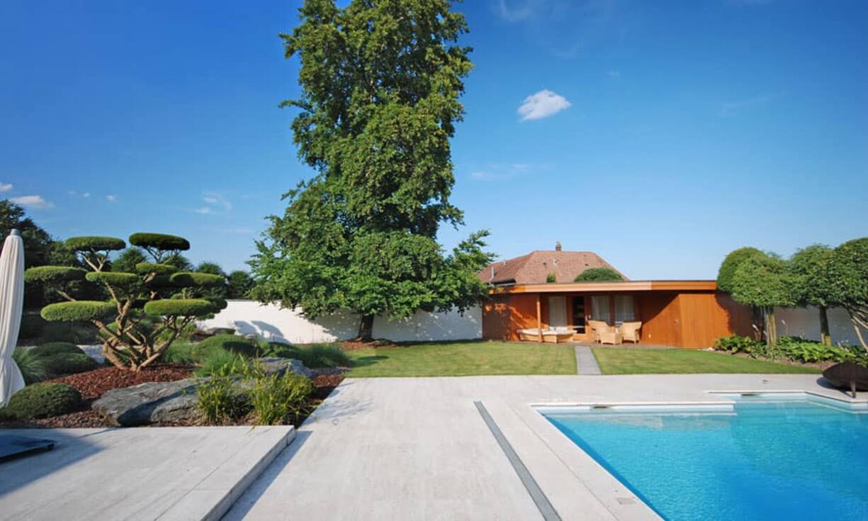 Der Aussenbereich der im Jahr 1976 erbauten Villa bietet mit dem Pool mit Badehaus und Sauna eine eigene, kleine Wellnessanlage.