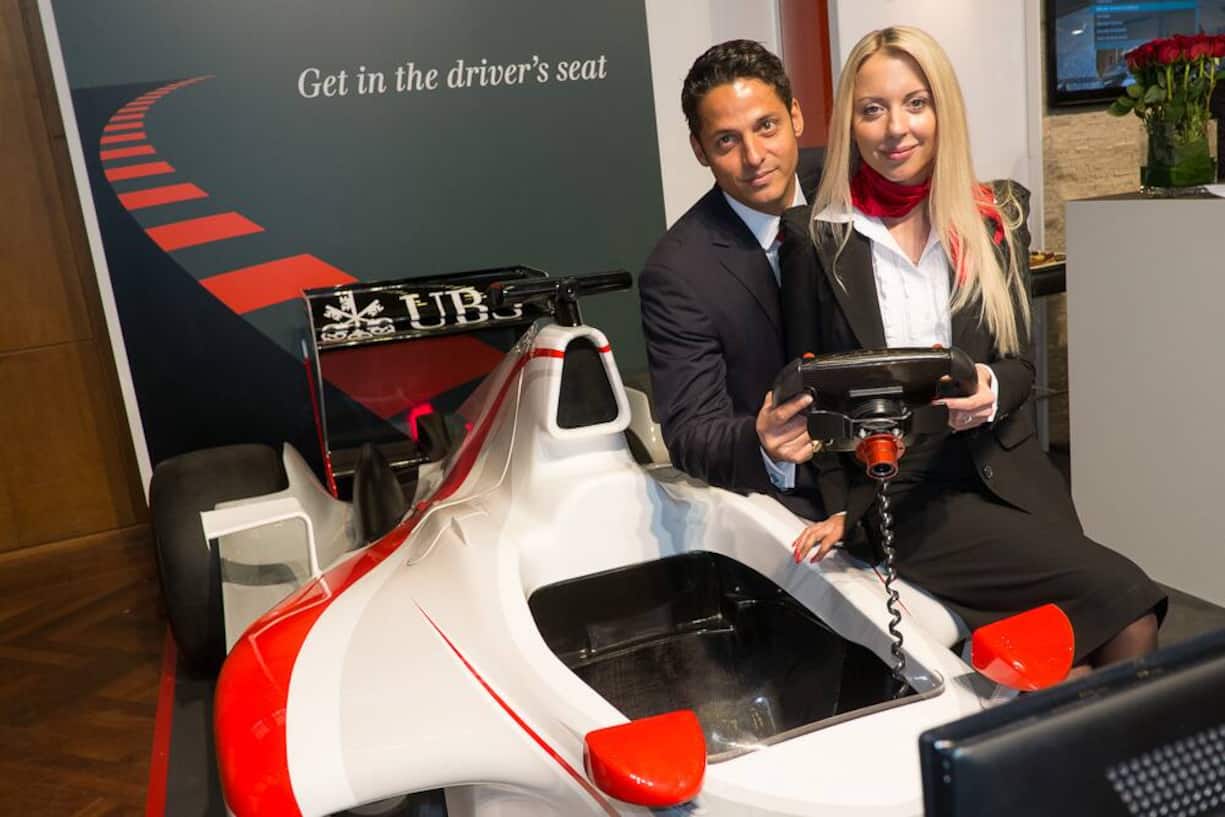 in the driver's seat: im Formel-1 Simulator am UBS-Stand. Robin O. Lemann, Director, UBS; Maria Lisevich, Marketing Manager UBS Investment Bank