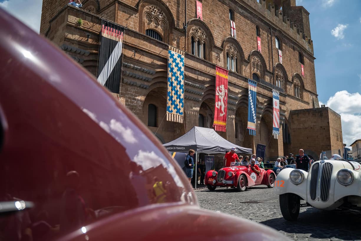 TRAUMHAFTE KULISSE Klassiker auf histori­ schem Pflaster. Im Hintergrund ein roter Fiat 110 (508 C) Sport von 1936, rechts ein BMW 328 von 1938.