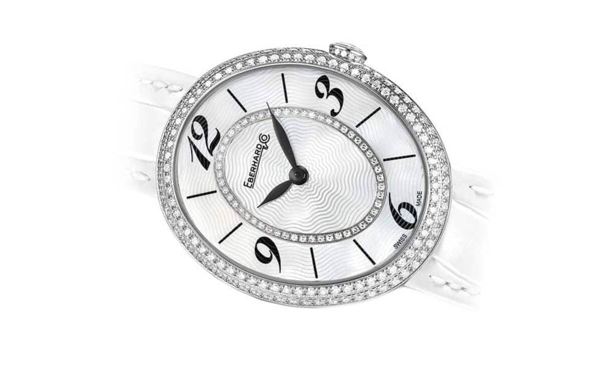 Eberhard & Co - Unschuldig 
Gilda Precious White 
Ganz in Weiss. Das elliptische Edelstahlgehäuse mit sanften, harmonischen Linien bildet das Umfeld für ein Perlmutt-Zifferblatt mit arabischen Ziffern auf der 3-, 6-, 9- und 12-Uhr-Position. Ein Mittelkreis aus 50 Diamanten bringt das Zifferblatt zum Funkeln. Zudem ziert eine Doppelreihe aus Diamanten die Lünette. Insgesamt 129 schillernde Edelsteine rahmen das Zifferblatt, 14 weitere Diamanten verleihen der Krone Glanz.