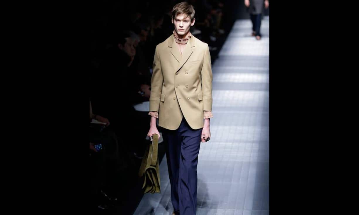 Ein beiger Blzaer, darunter ein Rollkragen mit Rüschen.