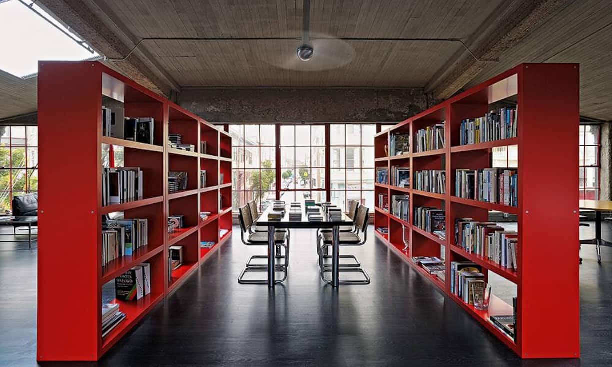 Die roten Expedit-Bücherregale von Ikea dominieren den grossen Wohnbereich. Die Cesca-Stühle von Marcel Breuer verleihen dem Raum eine zeitlose Dynamik. Darüber hängt ein Cirrus-Deckenventilator von Ron Rezek.