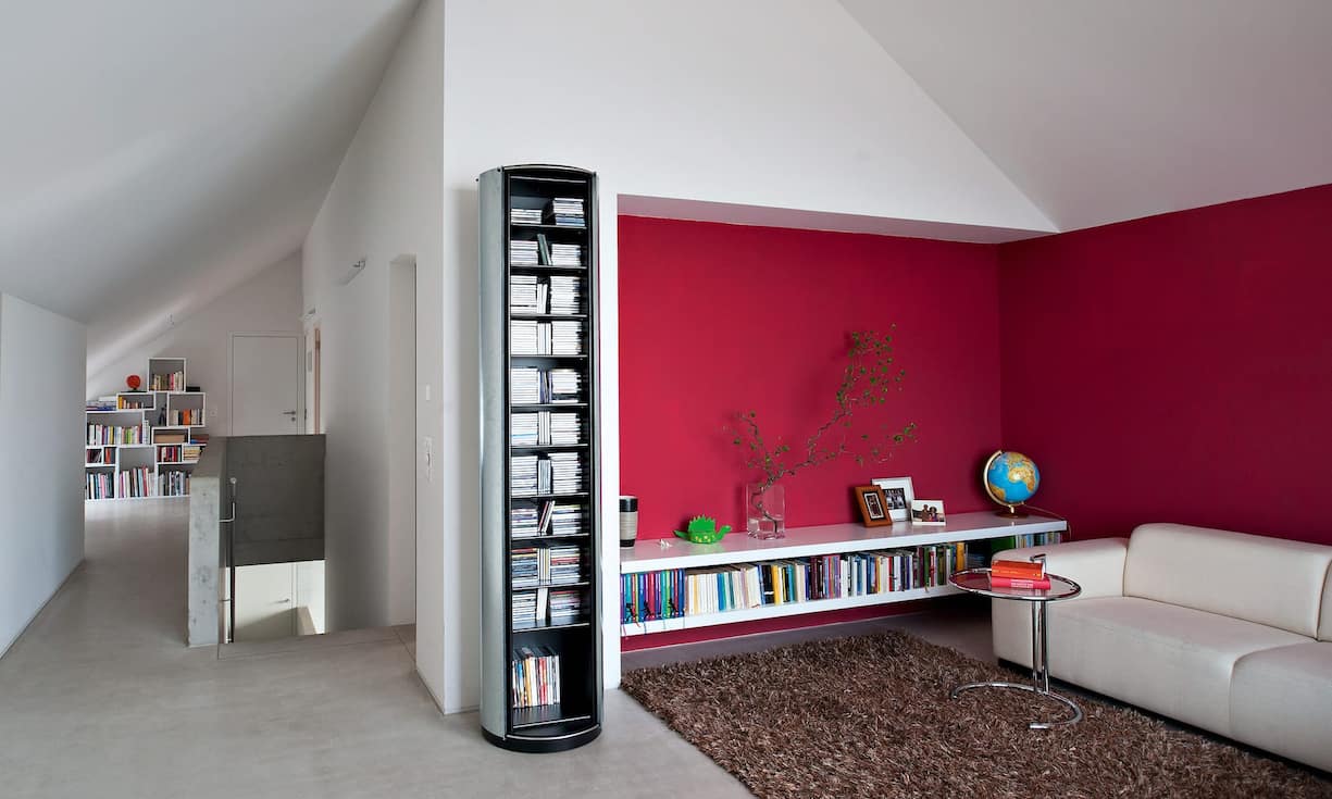 Das Dachgeschoss mit den Schlafzimmern und dem Leseplatz im Flur ist, anders als das Hauptgeschoss mit den Sichtbetonmauern, in Holzelementbauweise ausgeführt. Farbige Wände setzen in der Sofaecke einen kräftigen Akzent.