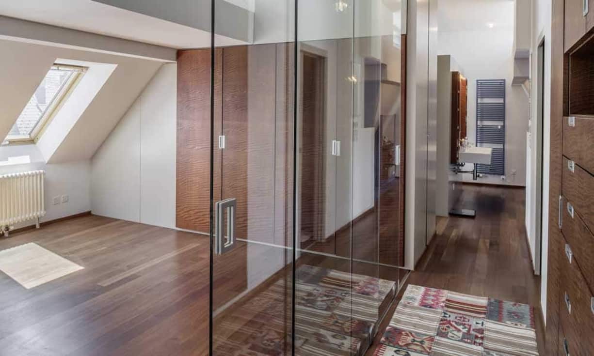 Auf der linken Seite der Wohnung befinden sich nebeneinander die drei geschlossenen Zimmer. Zuvorderst ein Gästezimmer, daneben ein Arbeits- oder Fitnesszimmer mit 3 Meter hohen Glaswänden.