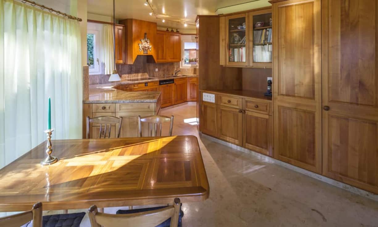 Die Echtholz-Küche aus Kirschbaum lässt sich problemlos mit dem Freisitz verbinden. Ein offenes Cheminée mit dazugehörigem Aussenwirtschafts-Abteil erleichtern eine Bewirtung von grösseren Gruppen.