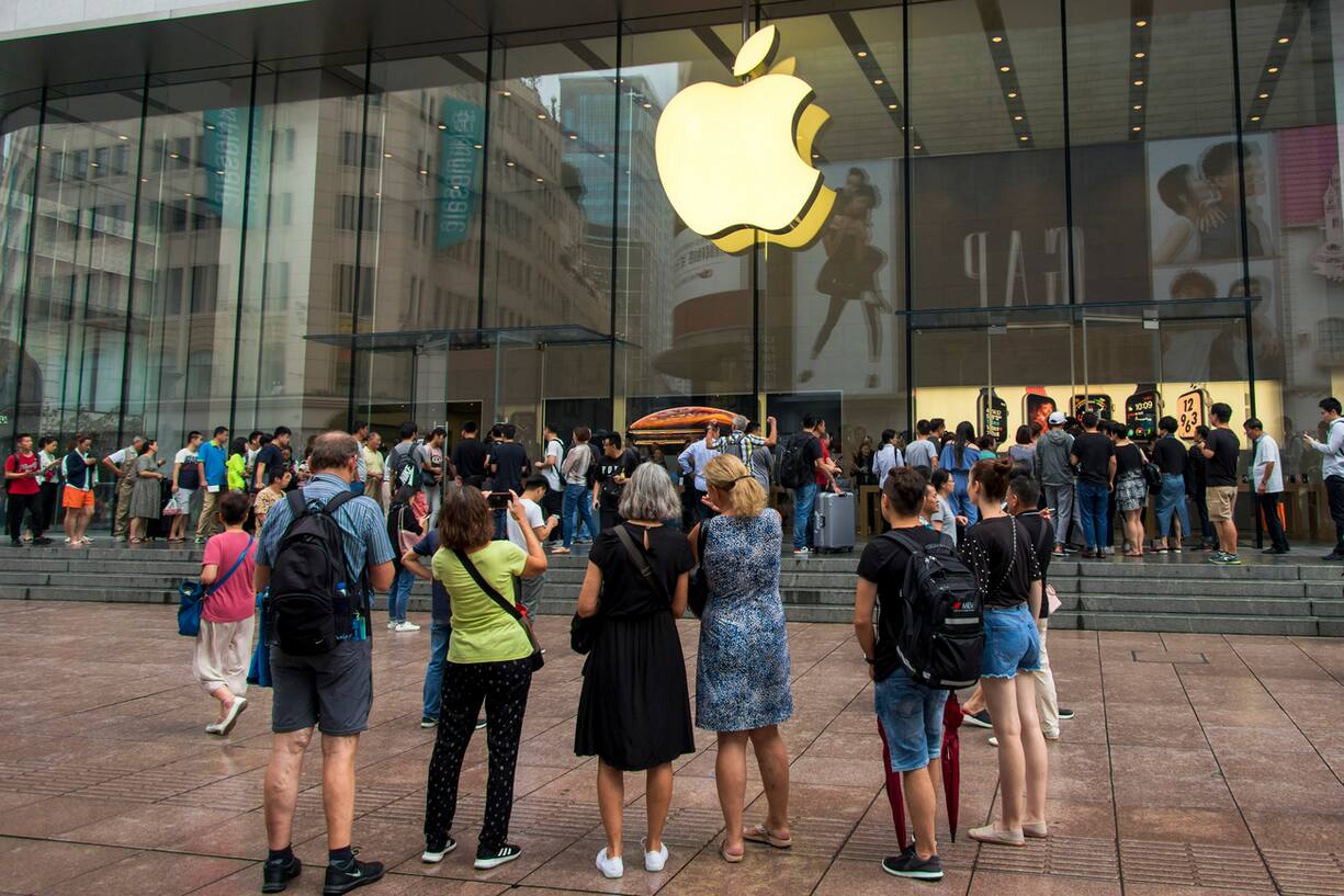 In this Friday, Sept. 21, 2018, photo, foreign tourists watch people queue in line to enter the Apple Store for the debut of the latest iPhones in Shanghai. China imposed new tariff hikes on U.S. goods on Monday, Sept. 24, 2018, and accused Washington of bullying, giving no sign of compromise in an intensifying battle over technology that is weighing on global economic growth. (Chinatopix via AP) (KEYSTONE/AP CHINATOPIX/)