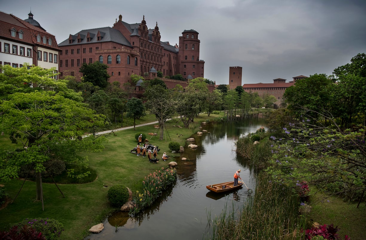 A worker cleans a waterway as office buildings are seen at Huawei's new sprawling 'Ox Horn' Research and Development campus on April 12, 2019 in Dongguan, near Shenzhen, China.