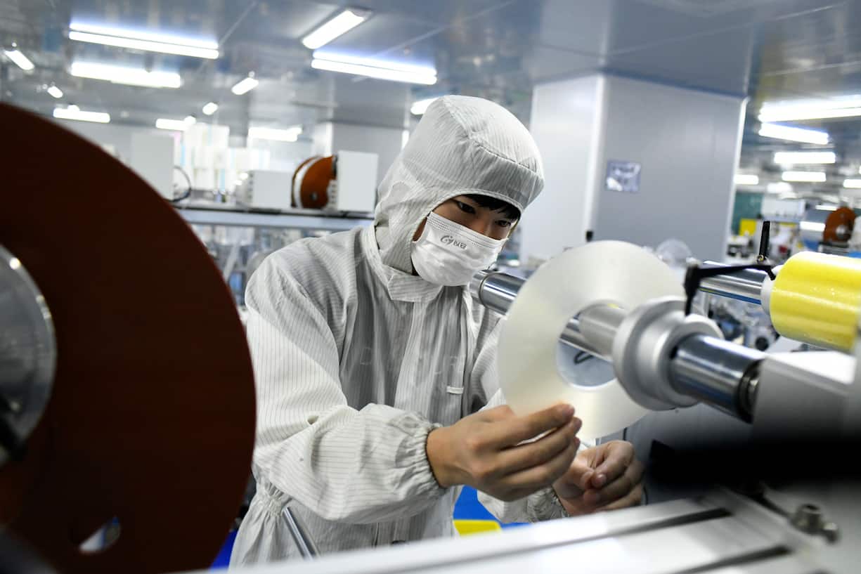 DONGGUAN, CHINA - MAY 20: Employees wearing protective suits work on the production line of optical film products at a workshop of Guangzhi Photoelectric Co., Ltd on May 20, 2020 in Dongguan, Guangdong Province of China. (Photo by Zhan Youbing/VCG via Getty Images)