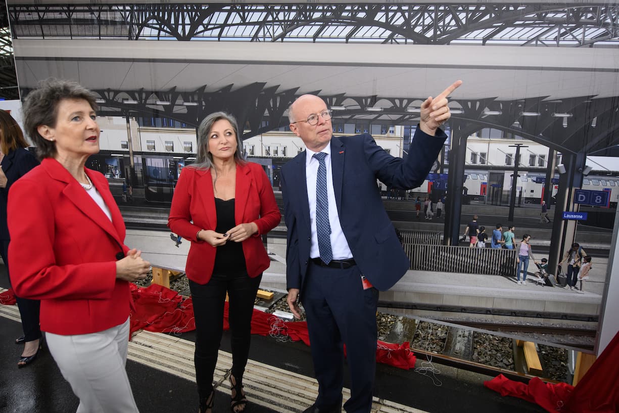 La Conseillere federale Simonetta Sommaruga, gauche, parle avec la conseillere d'Etat du canton de Vaud Nuria Gorrite, centre, et le CEO des CFF Vincent Ducrot, droite, devant une photographie geante representant la gare renovee lors du premier coup de pioche du chantier de la gare CFF de Lausanne, projet Leman 2030, ce mardi 29 juin 2021 a Lausanne. (KEYSTONE/Laurent Gillieron)