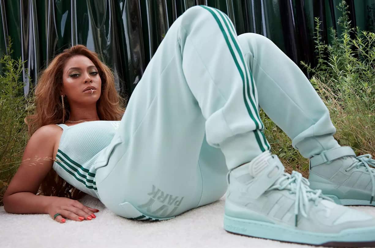 Beyoncé auf dem Rücken liegend und sich auf die Ellenbogen abstützend, in einem türkisfarbenen Adidas-Trainer.
