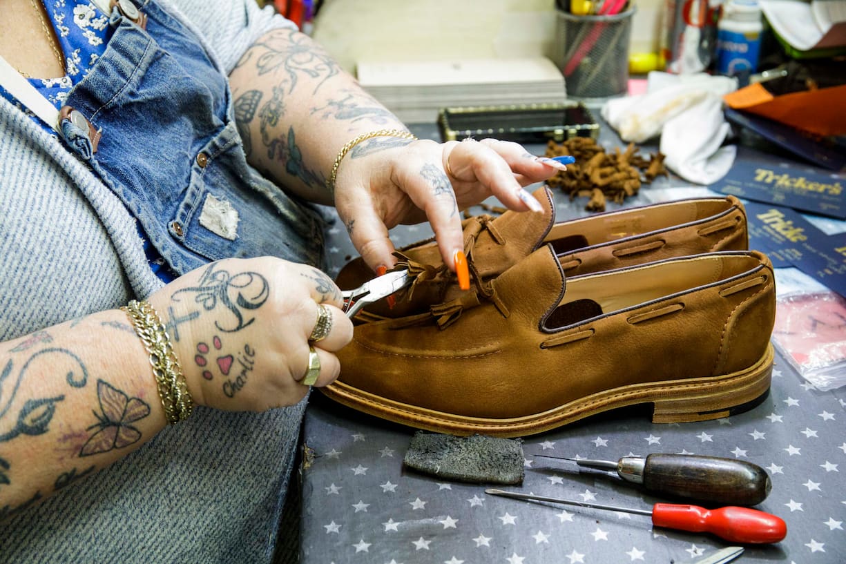 Mitarbeiterin stellt Schuhe fertig