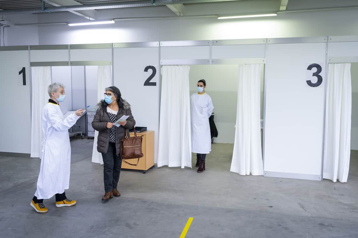 Une infirmiere parle avec une patiente apres une vaccination avec le vaccin Moderna lors de l'ouverture des centres de vaccination contre le Coronavirus (Covid-19) en Valais le mardi 2 fevrier 2021 a Sion. (KEYSTONE/Jean-Christophe Bott)