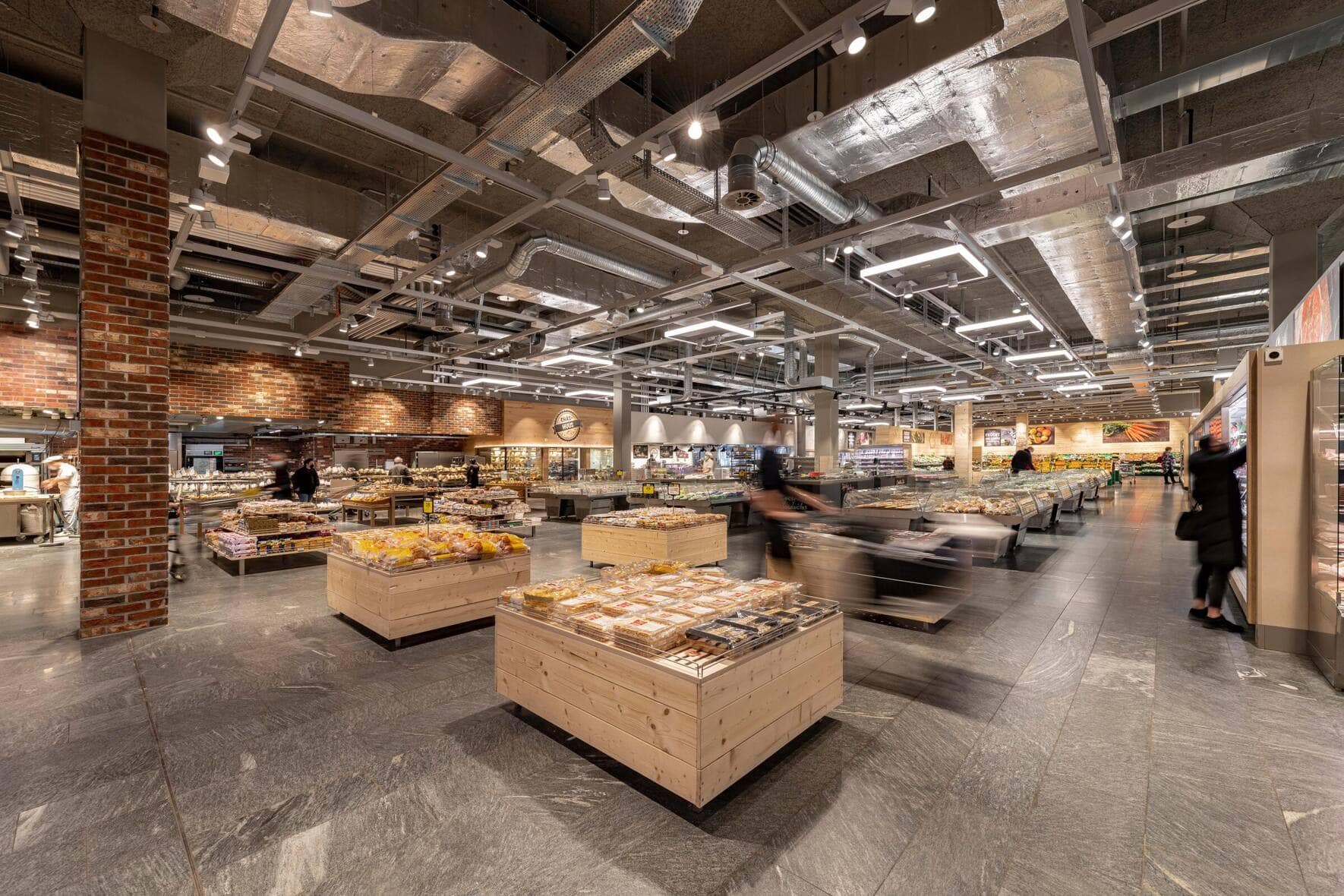 Coop vs. Migros: Supermärkte: Coop hat den Umbau aller Filialen von ­langer Hand geplant. Mehr Holz soll für Marktplatzstimmung sorgen, und in grossen Supermärkten stellt das Personal viele Produkte frisch her. Die Migros tüftelt noch an einem neuen einheitlichen Ladenkonzept und ist im Vergleich um Jahre im Rückstand.