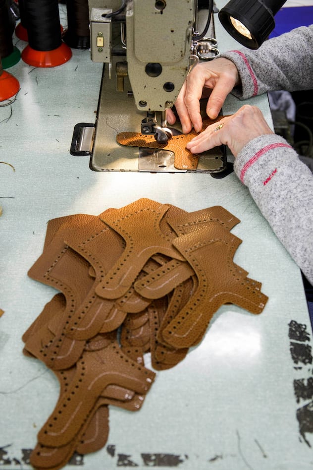 Einzelne Lederteile für Schuhe neben einer Näherin