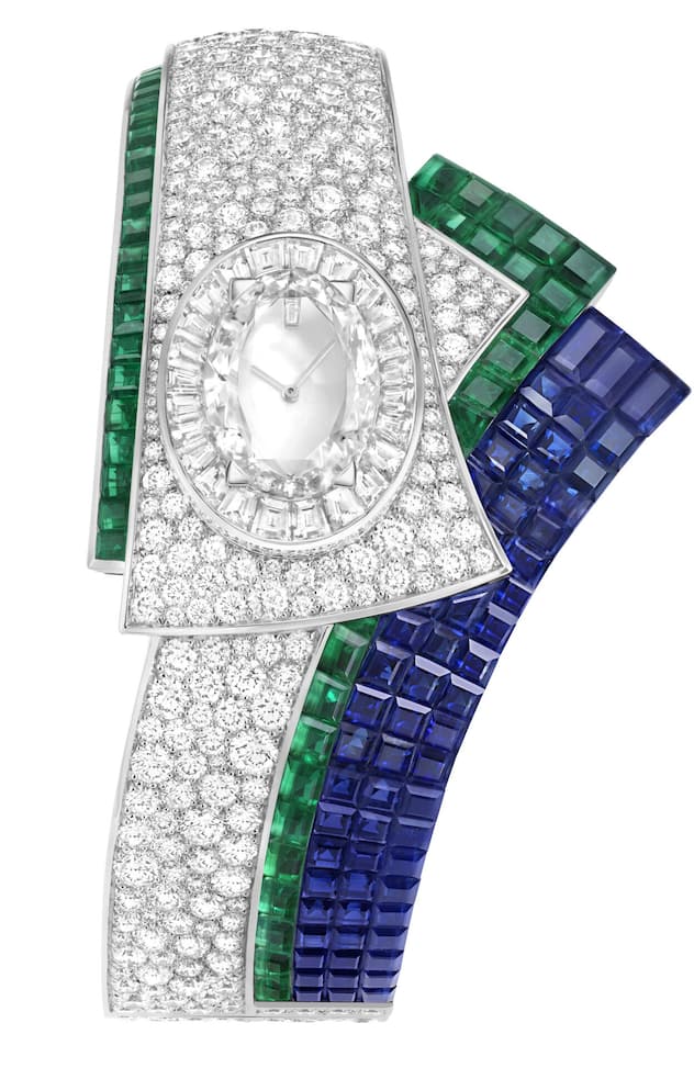 <p>Van Cleef &amp; Arpels</p>
<p>Handaufzugsuhr Ruban Mystérieux aus Weissgold mit Diamanten, Smaragden und Saphiren.</p>