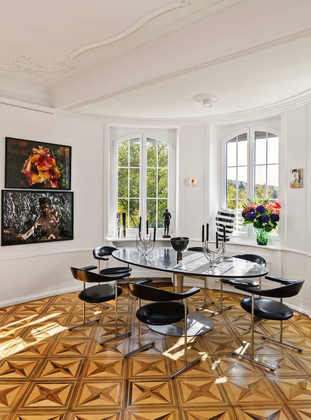 <p>Das Esszimmer bietet reizvolle Ausblicke ins Grüne und besticht durch historische Elemente wie Stuck und Intarsienparkett. Der Esstisch setzt sich aus einem Fuss von Knoll und einer massgefertigten Platte vom Schreiner zusammen. Die Stühle stammen aus einem Vintage-Laden.</p>