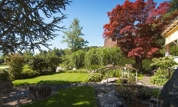 Die Villa mit ihrem grosszügigen Umschwung wurde 1945 erbaut. Der Garten wirkt dank altem Baumbestand und einem eigenen Bächlein wie ein kleiner Park.