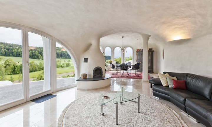 Das Esszimmer wiederum geht über in den Wohnbereich und wird von einem beidseitig einfeuerbaren Cheminée begleitet. Auf der ganzen Etage gibt es raumhohe Fensterfronten, welche auf die Terrassen führen.