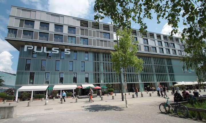 Die Wohnung befindet sich im 4. Stockwerk vom bekannten Puls-5-Gebäude. Es befindet sich zwischen ind er Näh des Hardturmstadions mitten in einer urbanen Umgebung. Das im Jahr 2004 eröffnete Gebäude beherbergt unter anderem Läden, Restaurants, Bars und einen Fitnesspark.