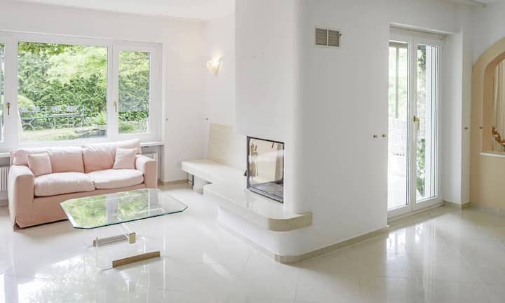 Das offen gehaltene Wohnzimmer mit Cheminée führt zu den beiden Wintergärten. Auf dieser Etage befinden sich zwei geschlossene Zimmer mit ca. 14 m² und 15 m² sowie  zwei attraktive Bäder.