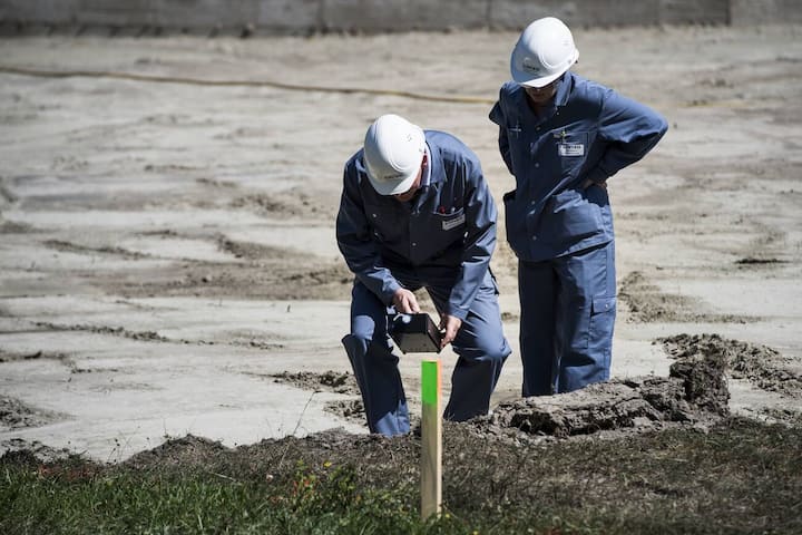 Des ouvriers de la Lonza font des mesures sur une parcelle pollue au mercure ce mercredi 6 juillet 2016 aux abords du terrain de sports Muehleye a Viege en Valais. L'entreprise Lonza, presente a la presse un projet d'assainissement pilote de parcelles contenant une pollution au mercure. (KEYSTONE/Jean-Christophe Bott)