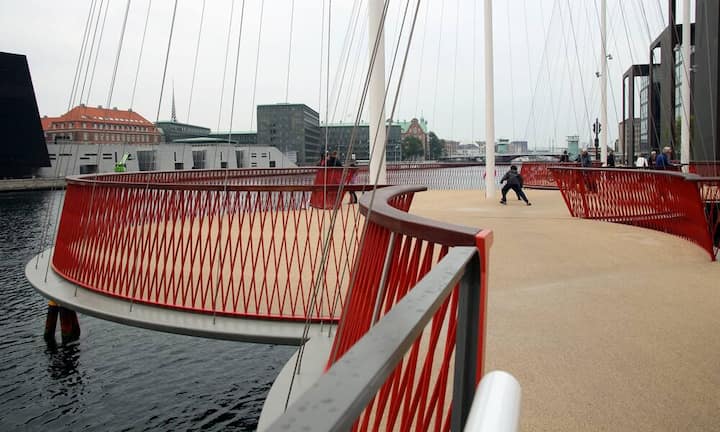 Cirkelbroen von Olafur Eliasson, 2015 (Kopenhagen, Dänemark)Von Kopenhagens Geschichte als Hafenstadt inspiriert, entwarf der Künstler Olafur Eliasson die Cirkelbroen-Brücke. Mit den fünf runden Plattformen und den verdrahteten Masten entsteht der Eindruck von im Hafen treibenden Booten. Flickr/Bex Walton