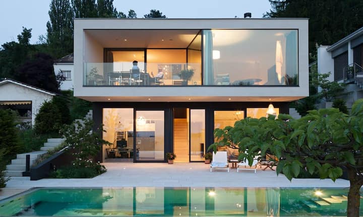 Die Betonwände der Sockelebene des Familienhauses haben einen lavaschwarzen Anstrich, der den Eindruck vermittelt, das Muttenzer Haus rage aus dem Berg heraus. Darüber hebt sich die helle Fassade mit Besenstrichputz ab.