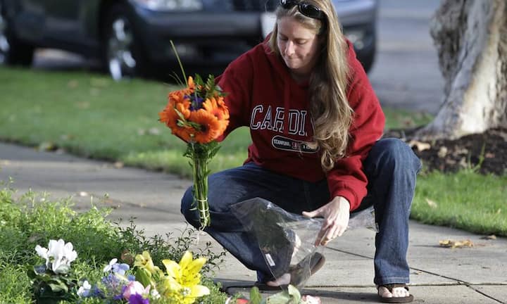 Vor dem Haus von Steve Jobs in Palo Alto legt eine Nachbarin Blumen nieder, ...