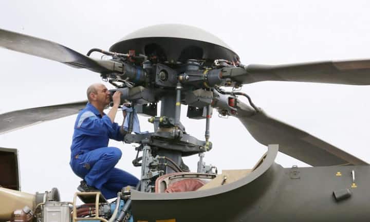 Ein Mitarbeiter reinigt den Roto eines Schweizer Super Puma Helikopters SA-332.