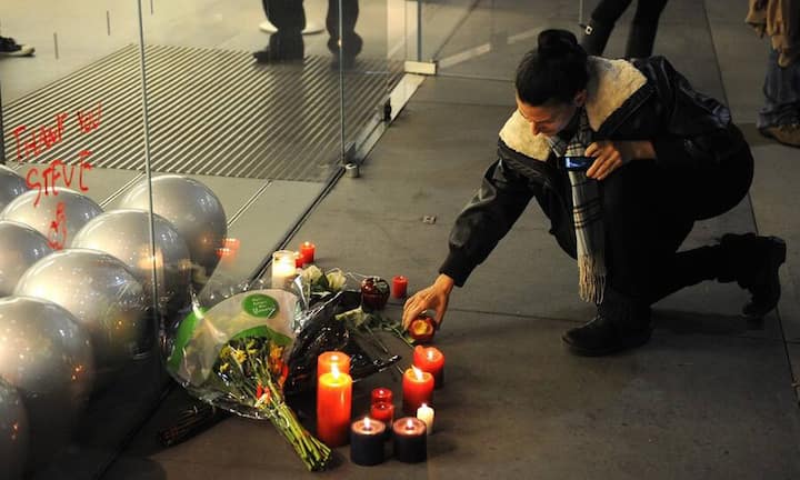 Vor einem Apple Store in Santa Monica, Kalifornien, stellt eine Frau eine Kerze auf, ...