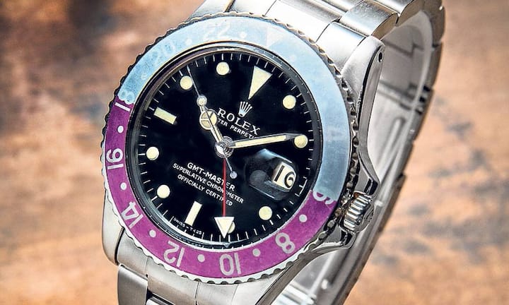 Rolex 1968: Oyster GMT-Master (Ref. 1675) 
Poliertes und satiniertes Edelstahl- Gehäuse mit bidirektional drehbarer, rot-(pink-)blauer 24-Stunden-Lünette. Mattschwarzes Zifferblatt. Stundenindizes mit Leuchtmasse ausgeführt. Roter Pfeilzeiger für die 24-Stunden- Anzeige. Durchmesser 40 Millimeter. Automatikwerk (Kaliber 1570), geprüft in fünf Positionen sowie auf Hitze und Kälte. Stahlband. Mit Original-Uhrenbox sowie mit COSC-Gangschein. Preis: 19 500 Franken