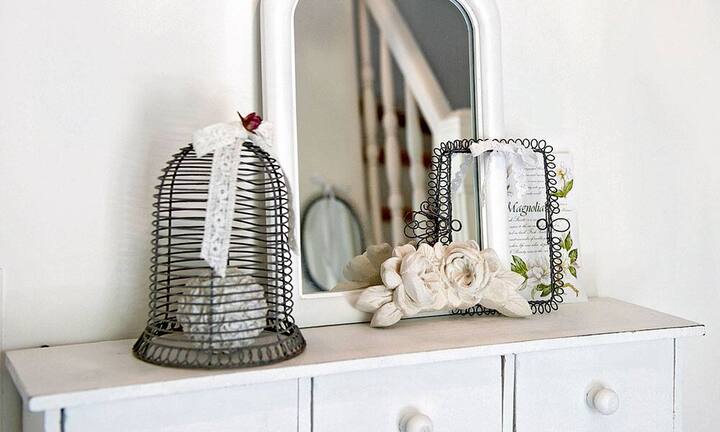 Detailliebe: Kleiner Vogelkäfig aus Draht, Spiegelchen und Blumen unterstreichen den rustikalen Chic.