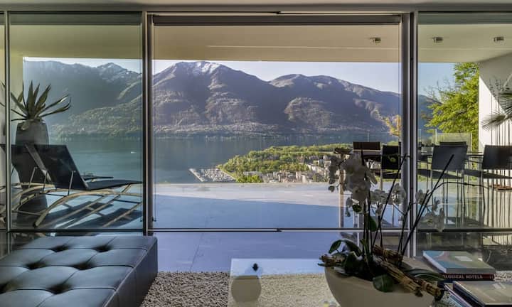 In der Attikawohnung verteilen sich 3,5 Zimmer auf einer Wohnfläche von 190 Quadratmetern. Vom Wohnzimmer aus mit bedeckter Terrasse blickt man direkt auf den Lago Maggiore und die umliegenden Berge.