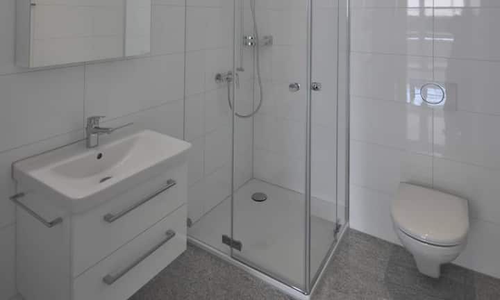 Badewanne und Waschküche sind im grösseren Badezimmer zu finden. Die Innenräume wurden in Weiss gehalten und die Böden mit hellgrauem Granit ausgelegt. Die Wohnung hat vier geräumige Zimmer.