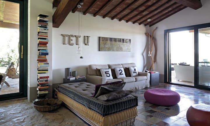 Liebe zum Detail: Was alt und stilvoll war, sollte erhalten und restauriert werden – wie etwa die Decke aus Kastanienholz oder der Boden aus Travertin-Steinen. Die Liege im Wohnraum besteht aus alten Matratzen, das Sofa ist eine Einzelanfertigung. Das Kunstwerk Tetu schuf Rossella Vasta.