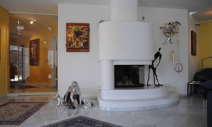 Der angegliederte Wohnraum lädt mit seinem schönen Cheminée zum Verweilen ein und bietet einen direkten Zugang zur gedeckten Terrasse, wo sich der grosse Garten und die sonnige Lage geniessen lässt.