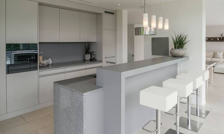 Die gut ausgestattete Küche mit Bar erlaubt direkten Zugang zum gedeckten Sitzplatz. Der Aussenbereich...