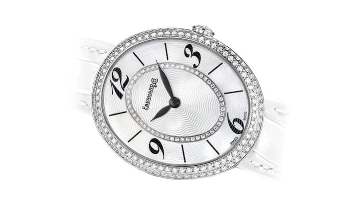 Eberhard & Co - Unschuldig 
Gilda Precious White 
Ganz in Weiss. Das elliptische Edelstahlgehäuse mit sanften, harmonischen Linien bildet das Umfeld für ein Perlmutt-Zifferblatt mit arabischen Ziffern auf der 3-, 6-, 9- und 12-Uhr-Position. Ein Mittelkreis aus 50 Diamanten bringt das Zifferblatt zum Funkeln. Zudem ziert eine Doppelreihe aus Diamanten die Lünette. Insgesamt 129 schillernde Edelsteine rahmen das Zifferblatt, 14 weitere Diamanten verleihen der Krone Glanz.