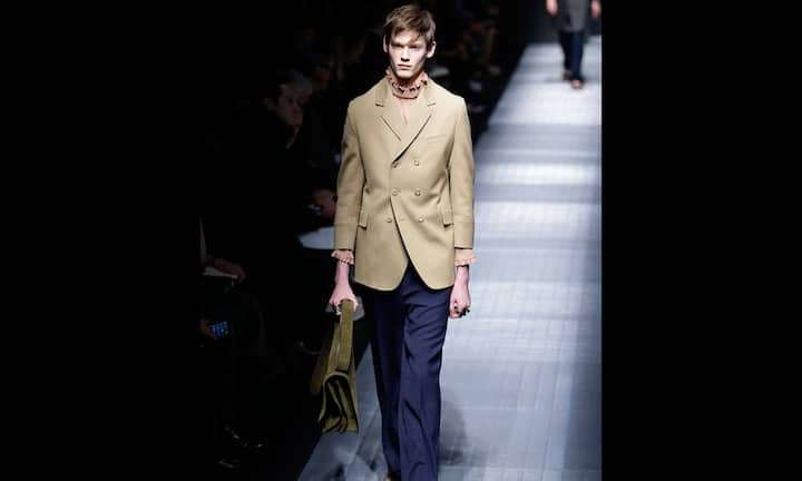 Ein beiger Blzaer, darunter ein Rollkragen mit Rüschen.