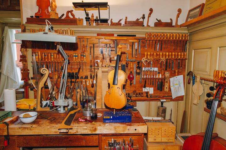 Werkstatt des Geigenbauers mit diversen Werkzeugen und einer Geige auf dem Werktisch.