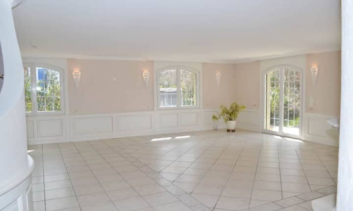 Das Wohnzimmer mit beinahe 70 Quadratmetern bietet genügend Platz um sich individuell einzurichten. Das integrierte Cheminée bringt Wärme in den in hellen Farbtönen gehaltenen Wohnraum.