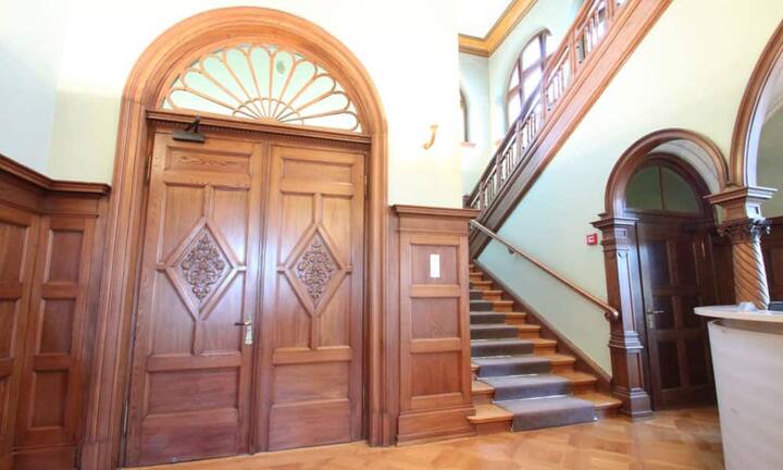 In der klassischen Eingangshalle mit einer Deckenhöhe von 8 Metern befindet sich ein breites Treppenhaus - auch ein Lift fehlt nicht.