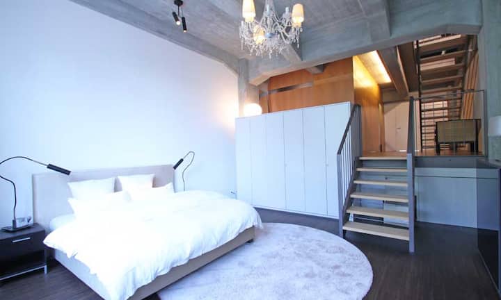 Die Loft-Wohnung bietet ein offenes Grundrisskonzept und der Wohnbereich verteilt sich auf verschiedene Ebenen. Die Zimmer besitzen teilweise eine Raumhöhe von knapp vier Metern.