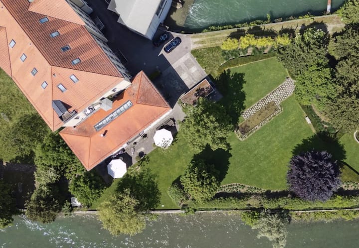 Sie ist an eine Fabrikhalle angebaut und verfügt über eine grosse Terrasse mit Sicht auf den Fluss.