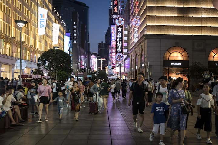 Pedestrians walk through the Nanjing Road shopping district at night in Shanghai, China, on Monday, July 29, 2019. Chinese trade negotiators will host their U.S. counterparts at a landmark of jazz-era Shanghai on the city's riverside Bund, re-opening trade talks with a marked change of atmosphere after an almost three-month hiatus. Photographer: Qilai Shen/Bloomberg