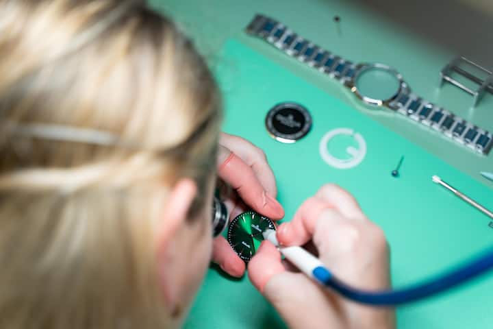 <p>Die Uhrmacherin reinigt nun mithilfe eines präzisen Instruments das Zifferblatt. So ist kein einziges Staubkörnchen auf der Uhr zu sehen.</p>