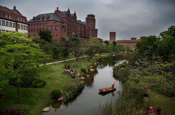 A worker cleans a waterway as office buildings are seen at Huawei's new sprawling 'Ox Horn' Research and Development campus on April 12, 2019 in Dongguan, near Shenzhen, China.