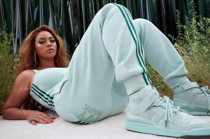 Beyoncé auf dem Rücken liegend und sich auf die Ellenbogen abstützend, in einem türkisfarbenen Adidas-Trainer.